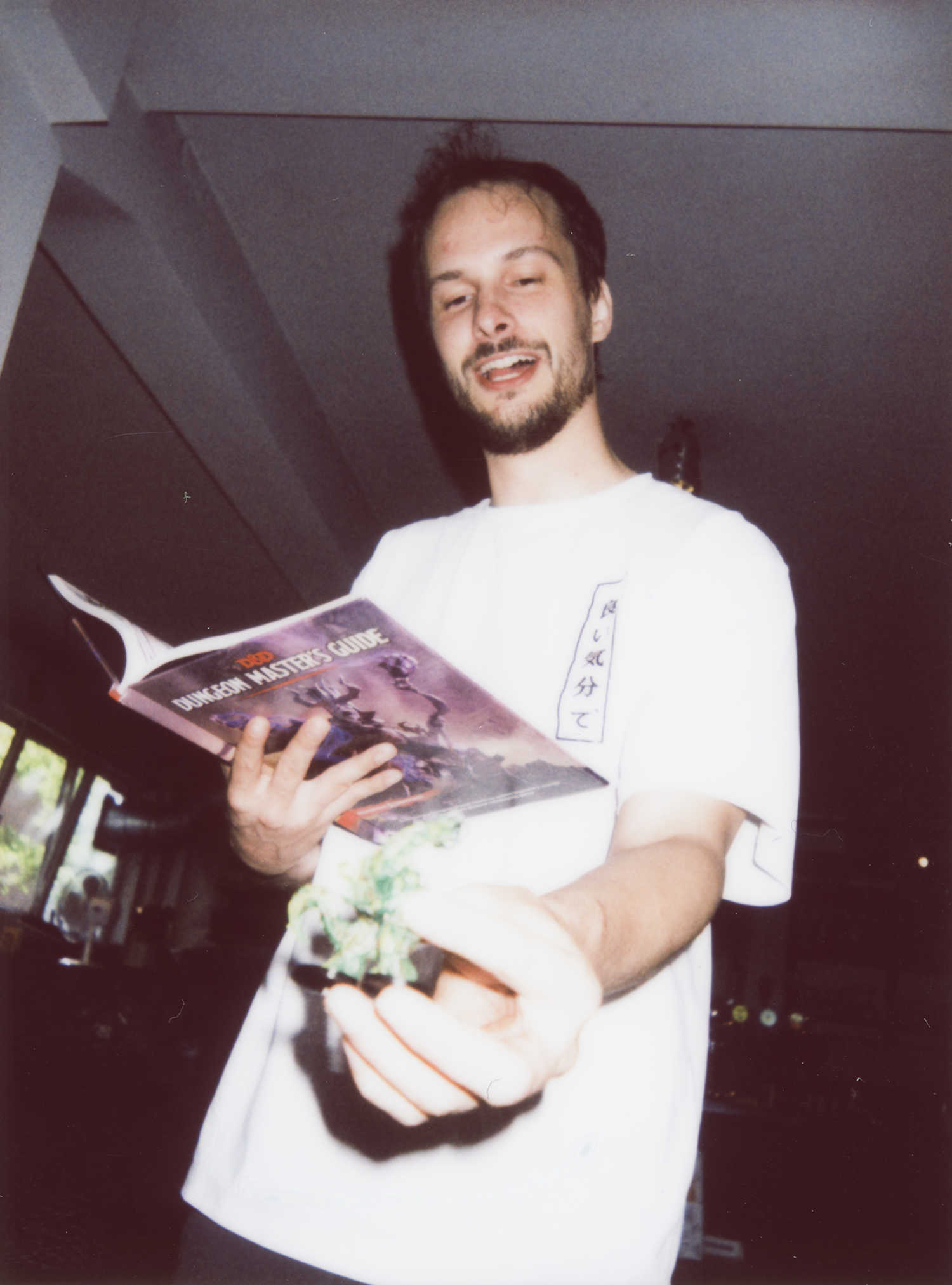 Tom van Eijk, Dungeon Master, laughing while reading the Dungeon Master's Guide and holding out a miniature